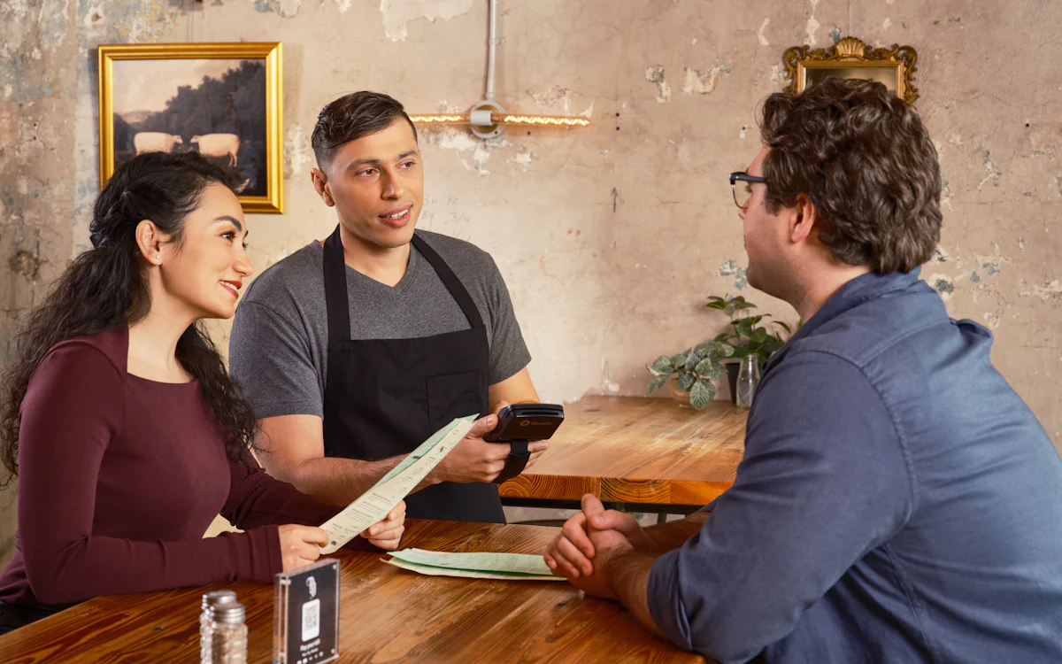 Cambrer prenent nota a uns clients d'un restaurant